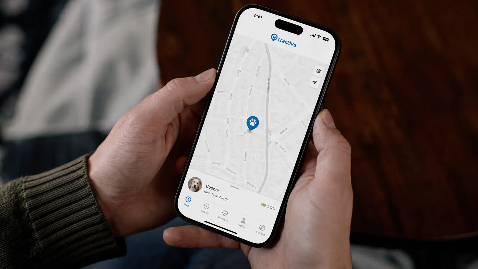 Smartphone screen showing the Tractive app live map with a moving dog location dot on a neighborhood street